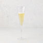 Small, clear scissor-cut glass champagne flute with a rippled rim, filled with bubbly champagne.