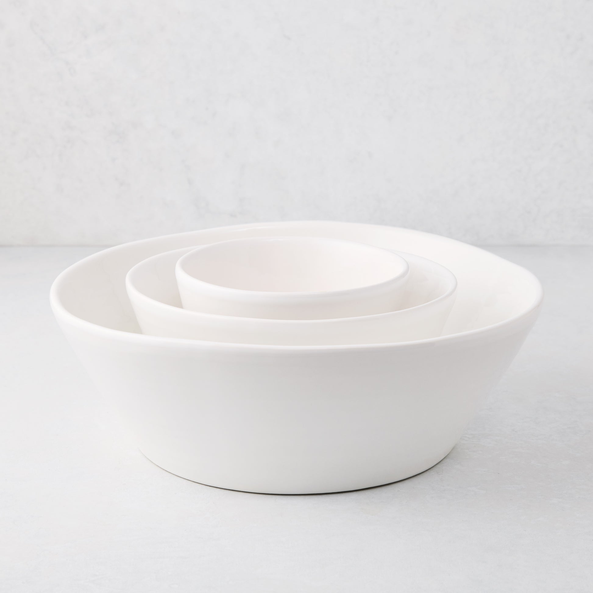 Set of three white spiral ceramic serving bowls, handmade in Portugal, nested on a light surface.