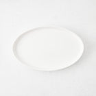 Small white oval stoneware serving platter with a minimalist design, 11.81 inches long.