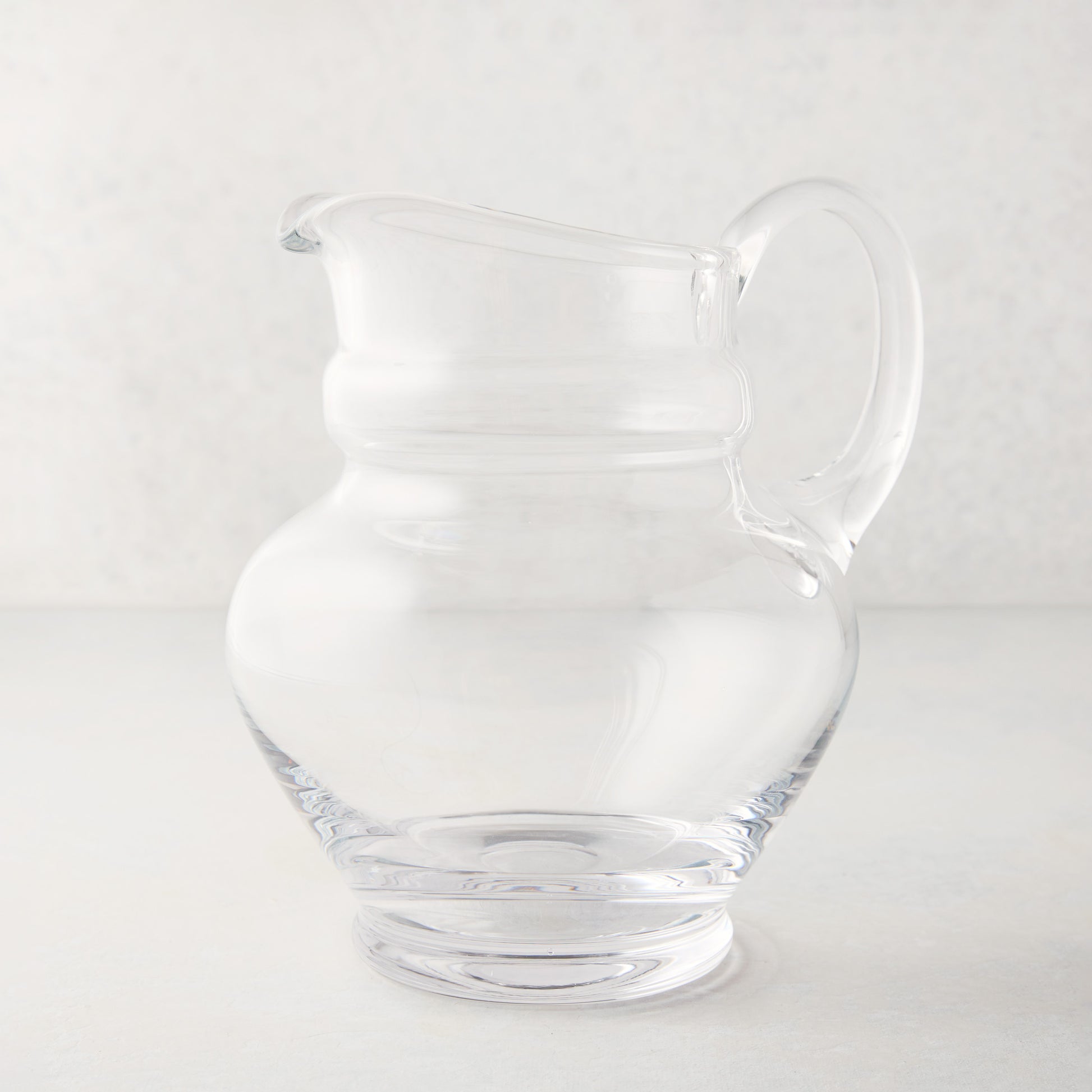 Clear, hand-blown Sutton Glass Pitcher with unique shape and handle.