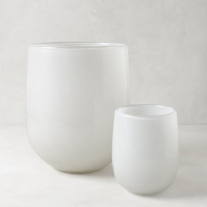 Two opaque white handblown glass barrel vases, one large and one small.