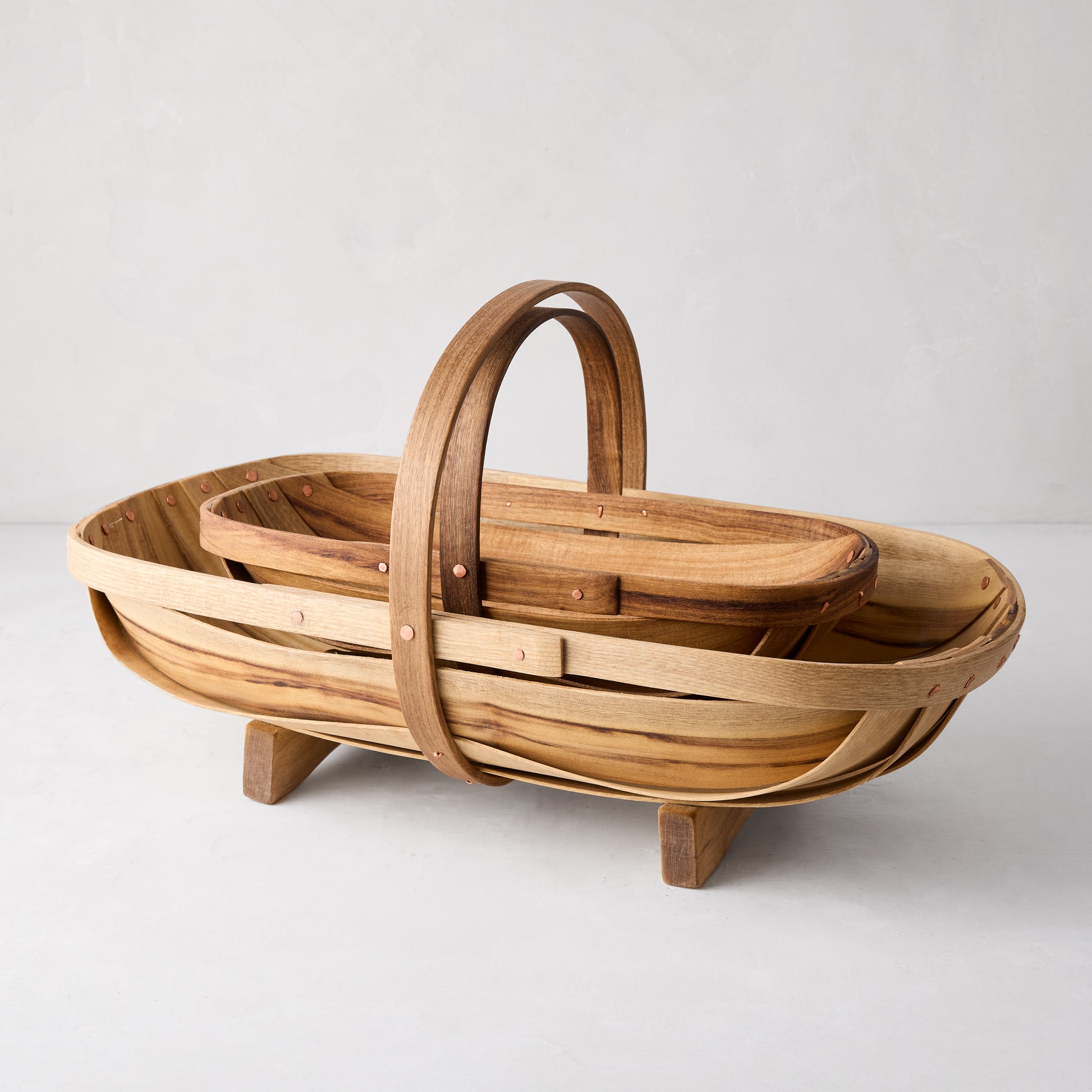 Two handcrafted wooden garden trugs, one small and one large, with handles and copper nails.