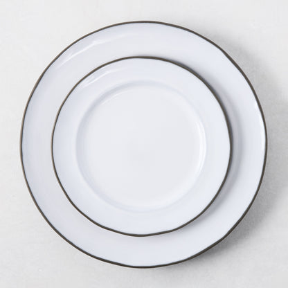 Two white enamelware plates with dark rims, stacked.