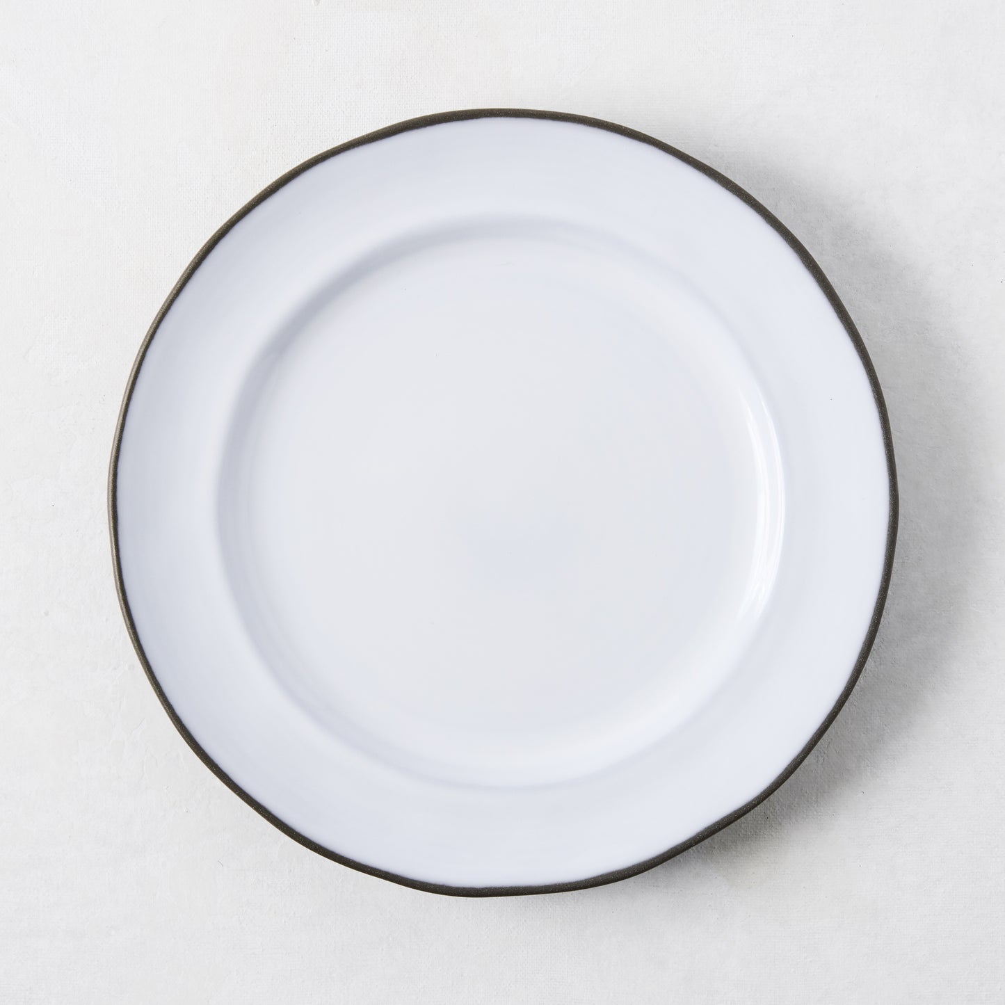 White enamelware salad plate with a dark rim.