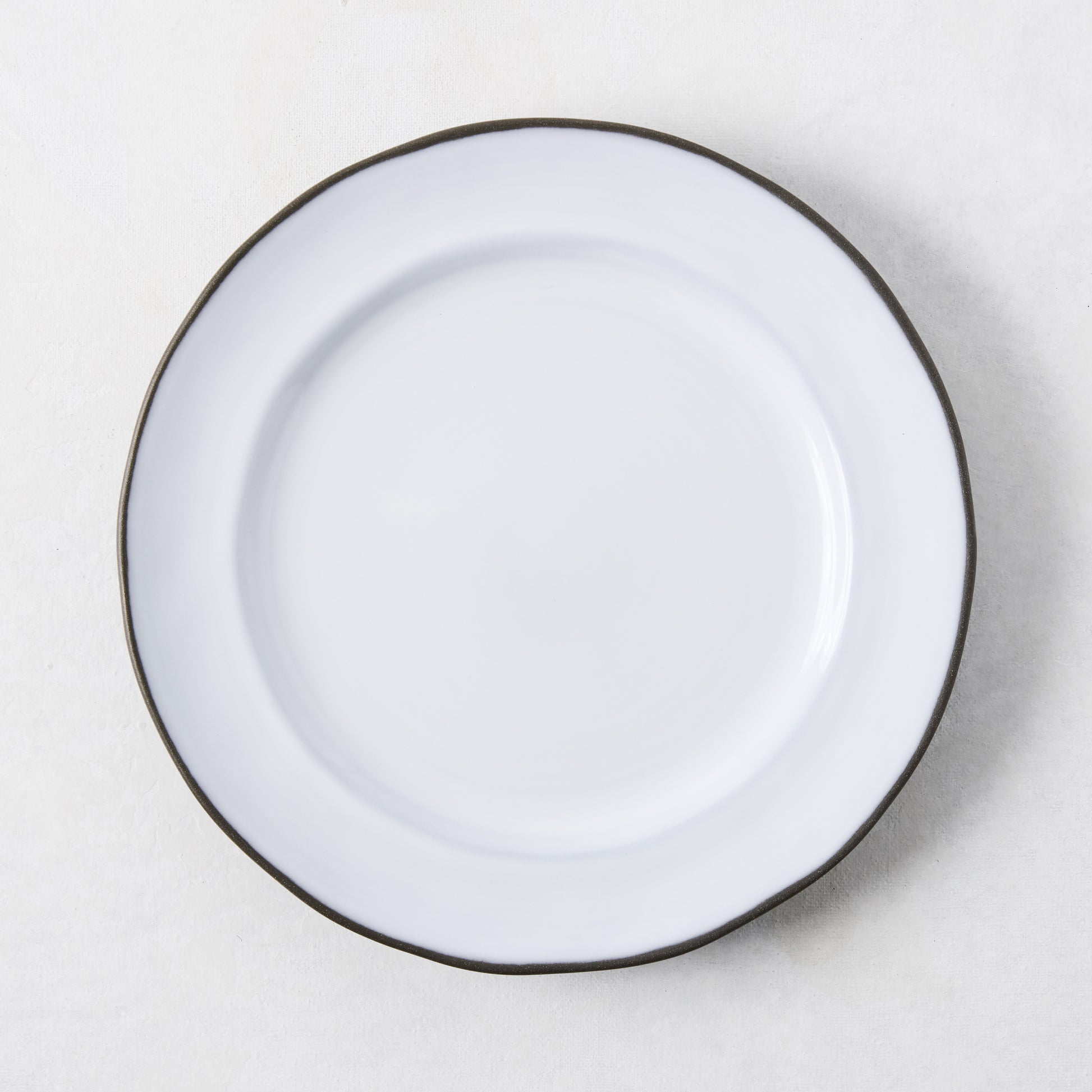 White enamelware salad plate with a dark rim.
