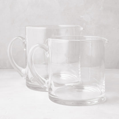 Two clear, hand-blown glass Soho Short Pitchers, one 40 oz and one 56 oz, with handles and spouts.