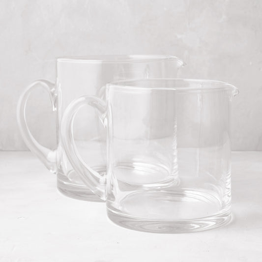 Two clear, hand-blown glass Soho Short Pitchers, one 40 oz and one 56 oz, with handles and spouts.