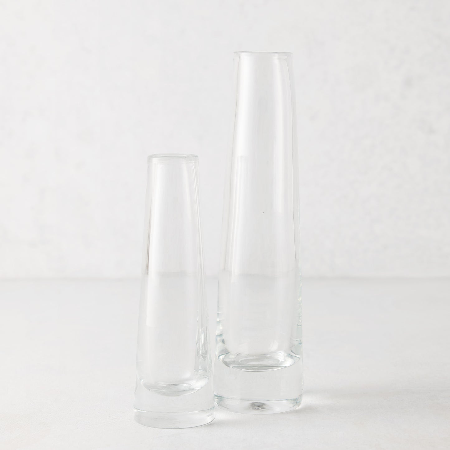 Two clear Solifleur mouth-blown glass bud vases, one small and one tall, on a white surface.