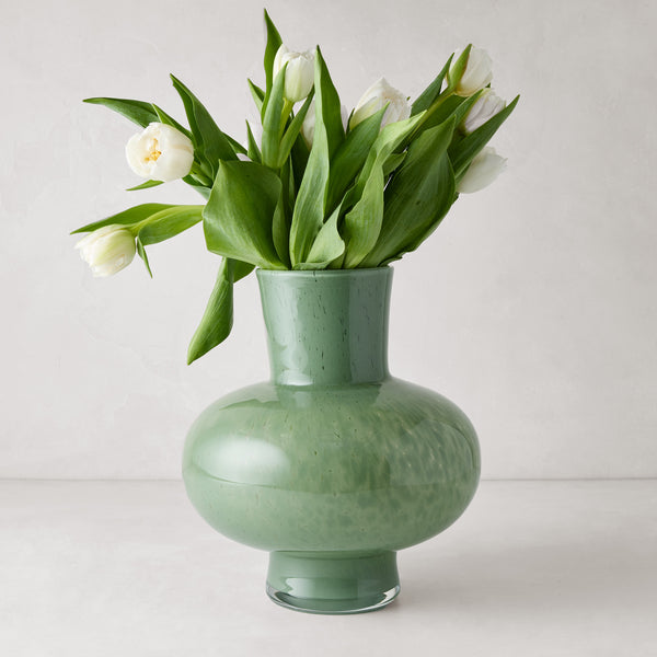 Sonia oversized opaque green handblown glass vase with white tulips.