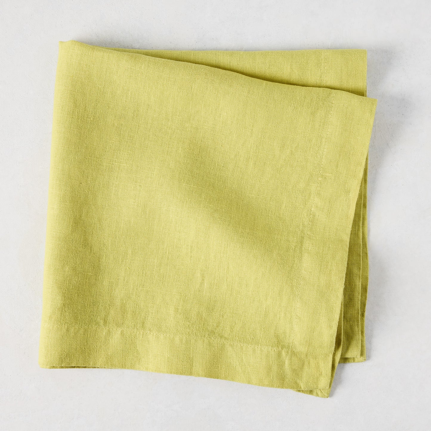 HG Sour Apple hand-dyed linen napkin, 22-inch square, folded on a light background.