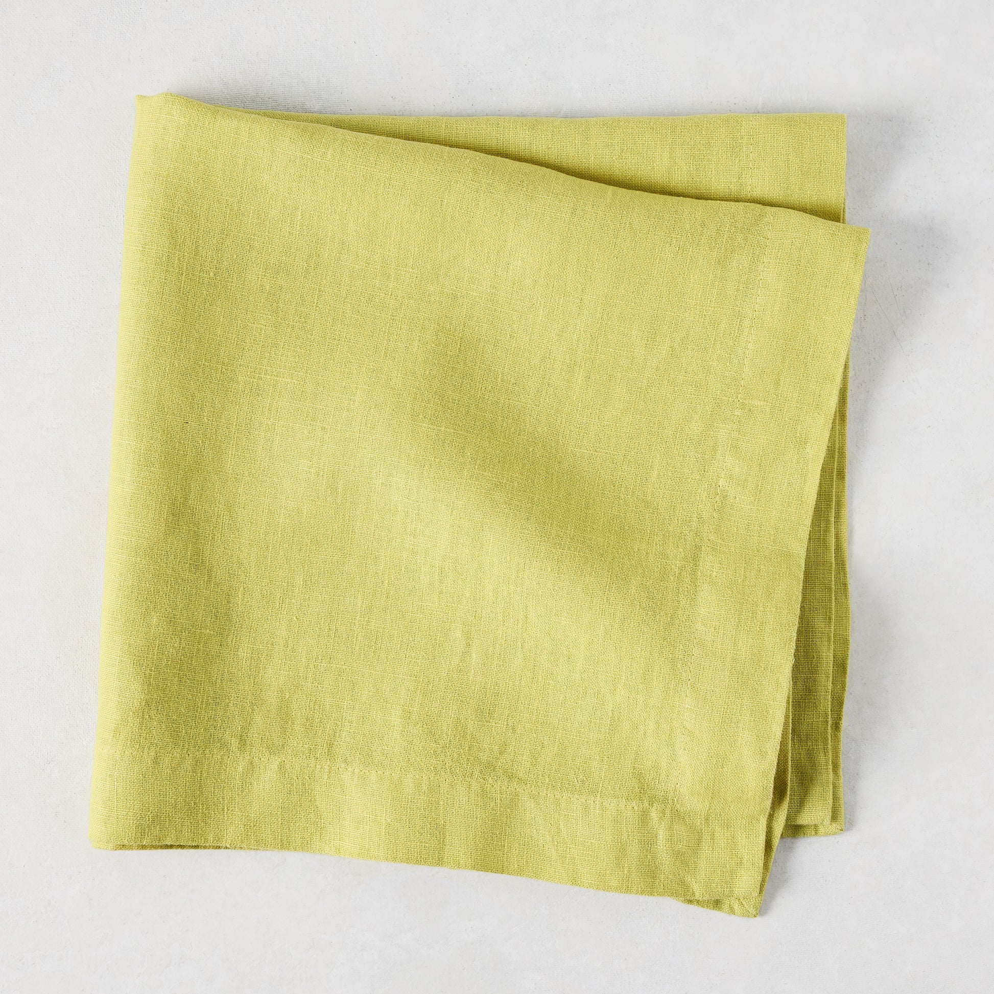 HG Sour Apple hand-dyed linen napkin, 22-inch square, folded on a light background.