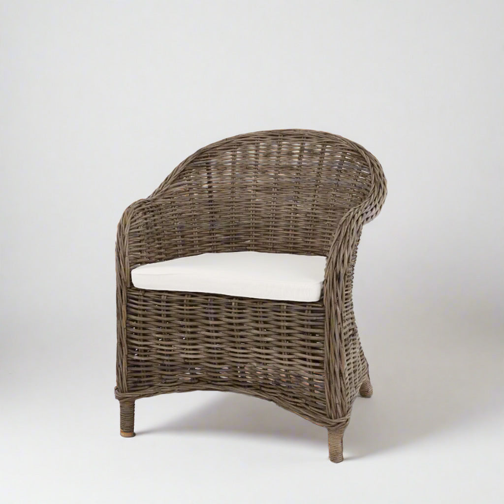 Southern French Arm Chair, natural rattan with woven texture and white cushion.