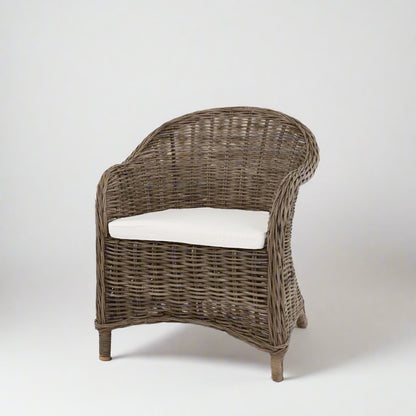 Southern French Arm Chair, natural rattan with woven texture and white cushion.