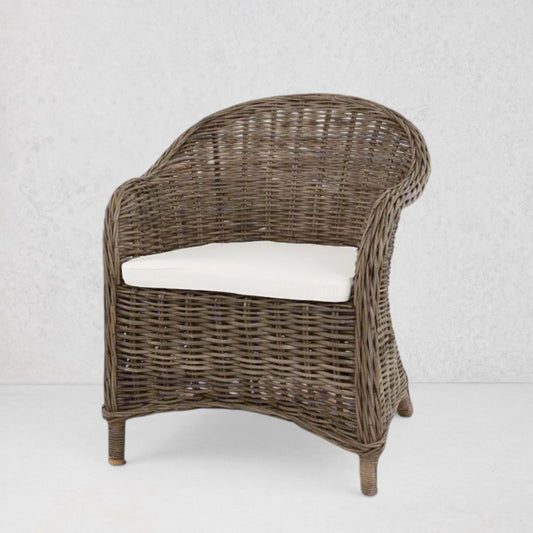 Southern French Arm Chair, natural rattan with woven texture and white cushion.