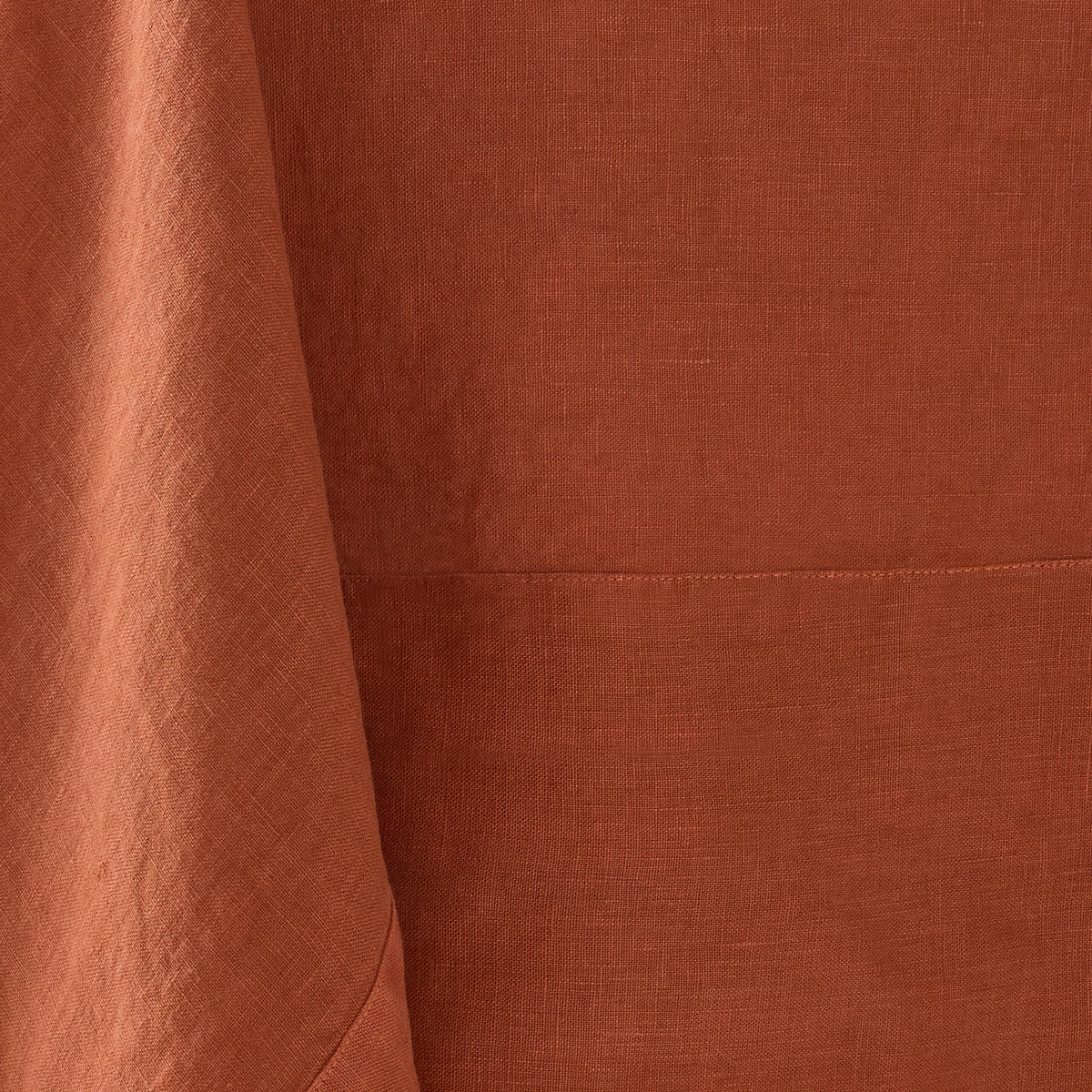 Spice-colored hand-dyed 100% linen tablecloth with visible fabric texture and a stitched border detail.