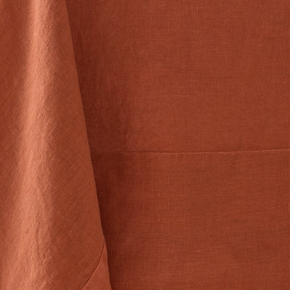 Spice-colored hand-dyed 100% linen tablecloth with visible fabric texture and a stitched border detail.