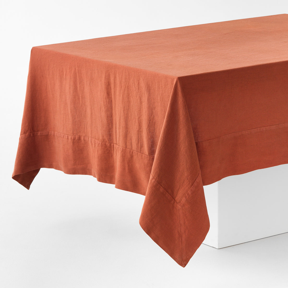 Spice-colored hand-dyed 100% linen tablecloth with 5-inch mitered corner detailing on a white table.