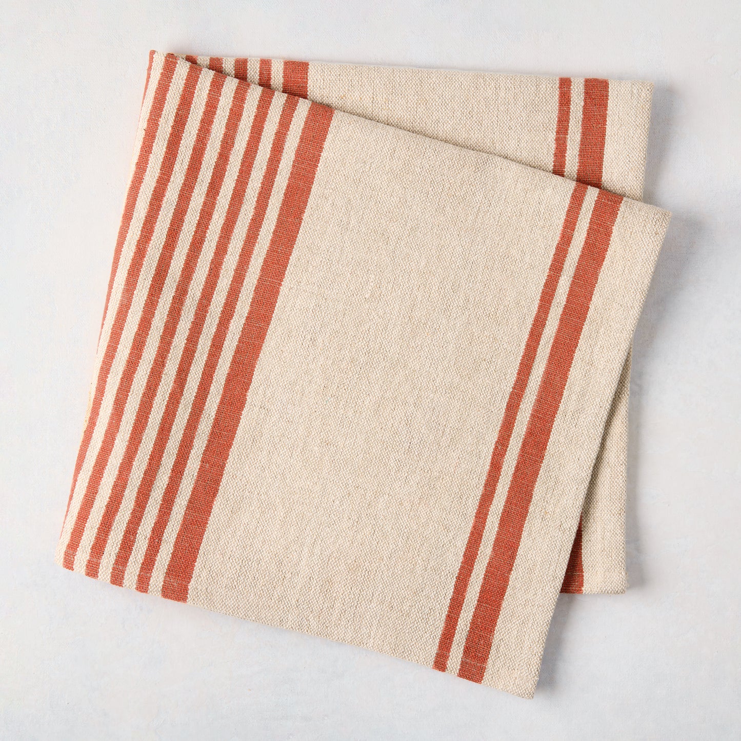 Folded Spice Orange Boat Stripe Natural Napkin, 50% cotton, 50% linen, with orange stripes on a beige base.