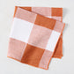 Spice orange buffalo check linen-cotton napkin, folded, 20" square.