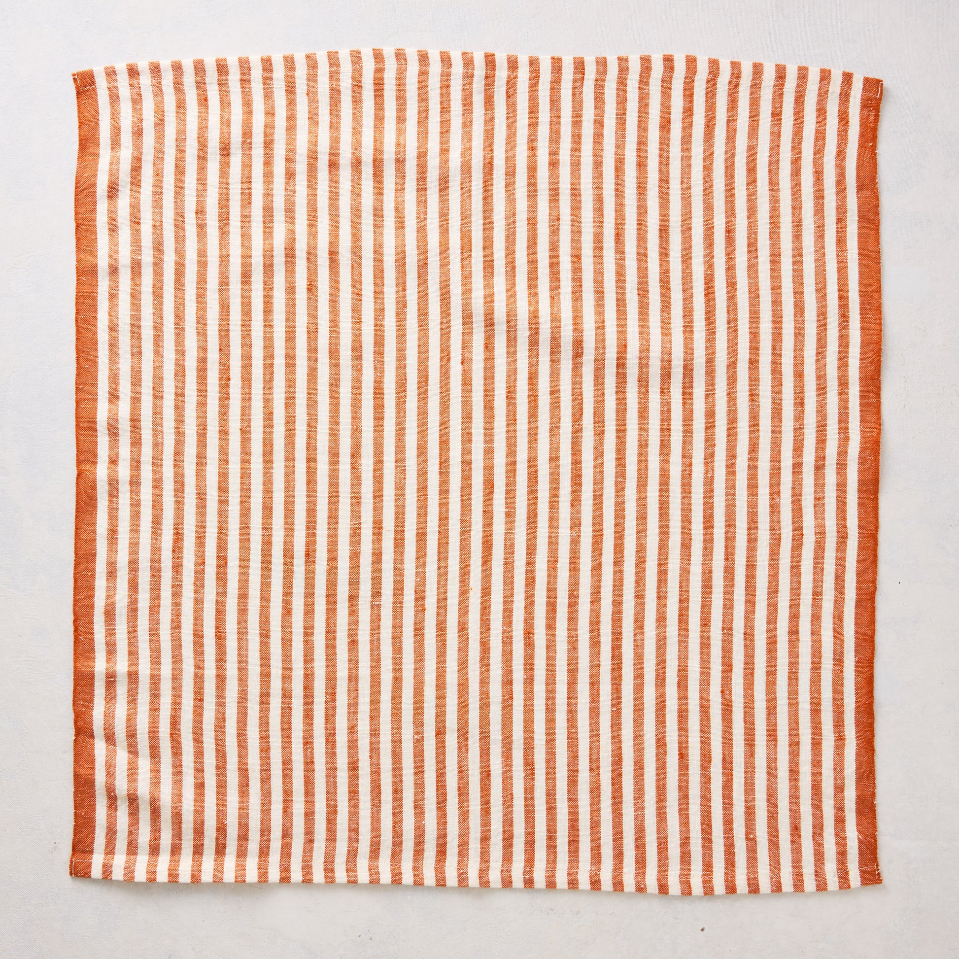 21-inch square linen napkin with orange and white ticking stripes and a solid orange border.