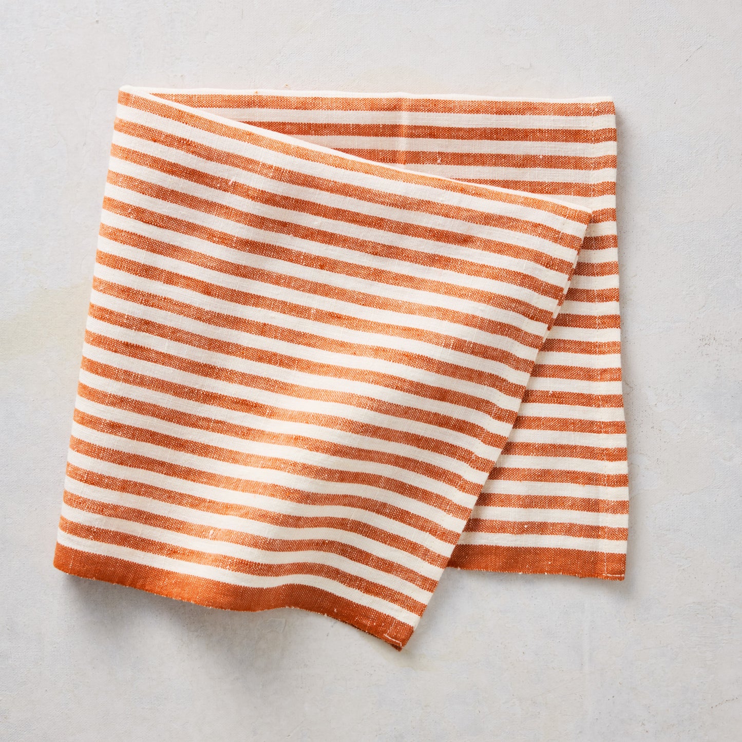 21-inch square linen napkin with orange and white ticking stripes and a solid orange border.