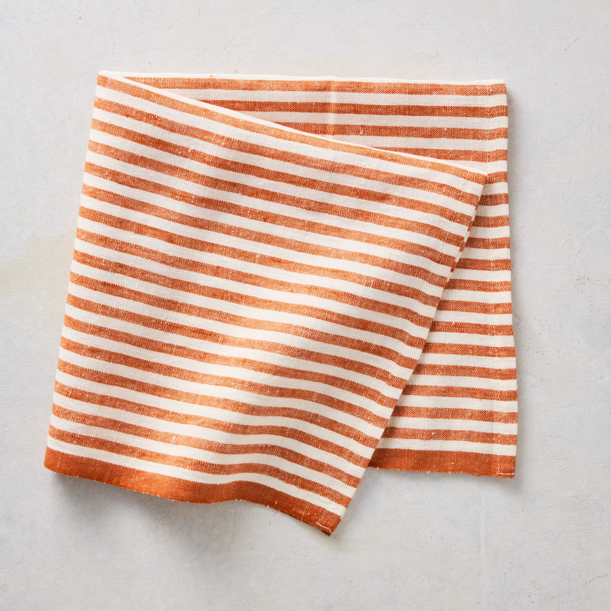 21-inch square linen napkin with orange and white ticking stripes and a solid orange border.
