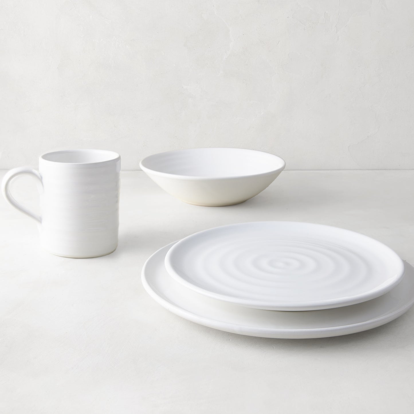 White ceramic dinnerware set: spiral dinner plate, salad plate, bowl, and mug.