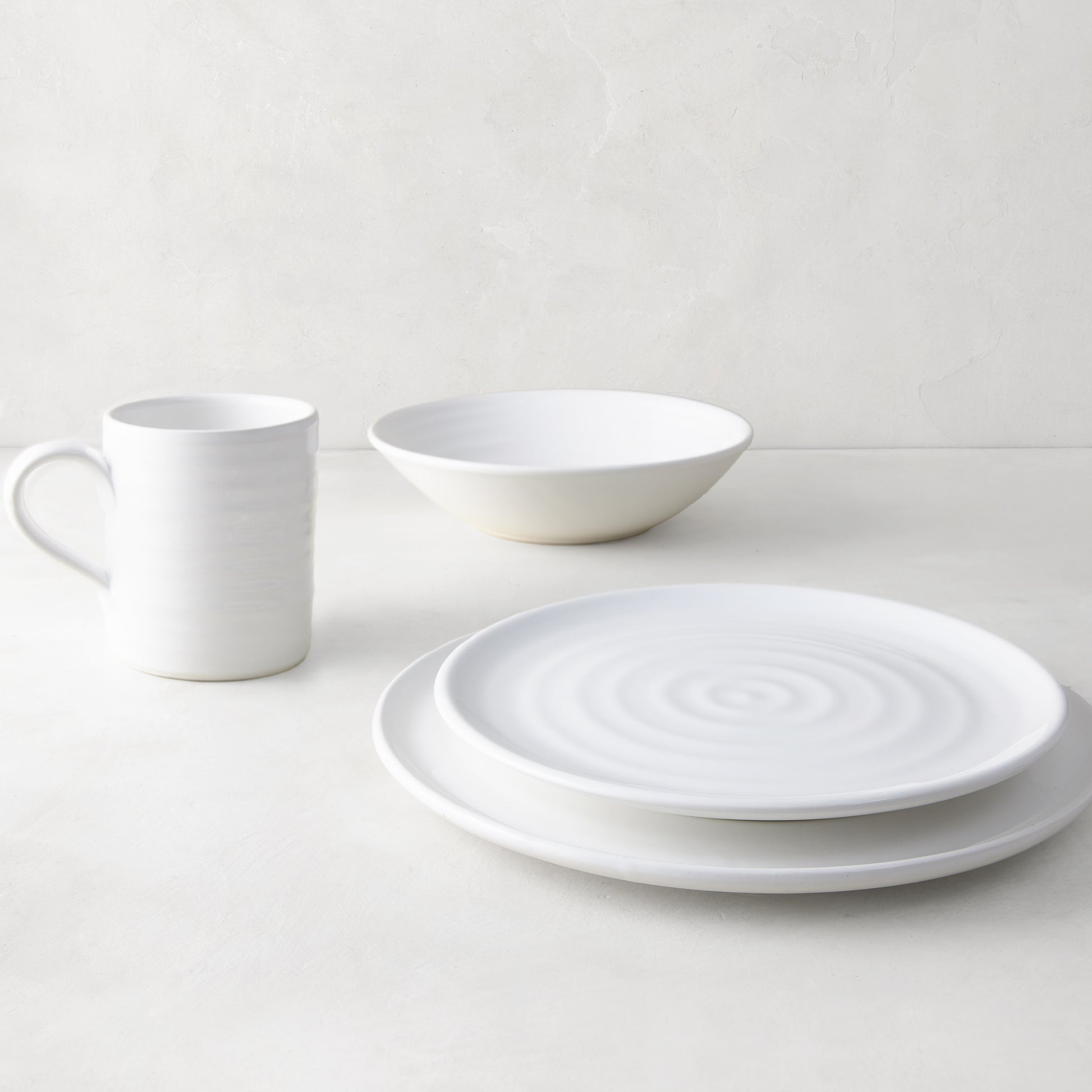 White ceramic dinnerware set: spiral dinner plate, salad plate, bowl, and mug.