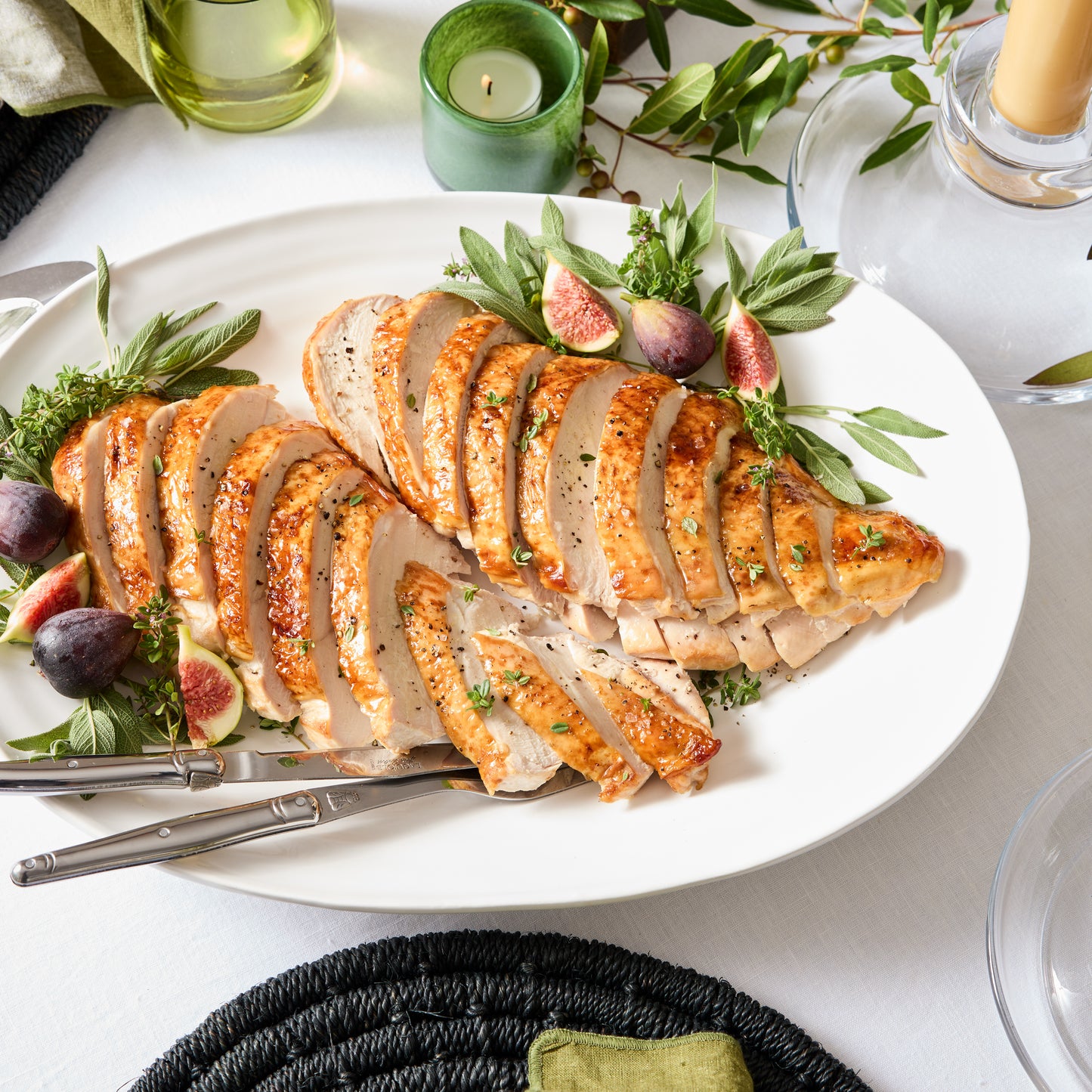 White ceramic oval platter with sliced turkey, figs, and herbs.
