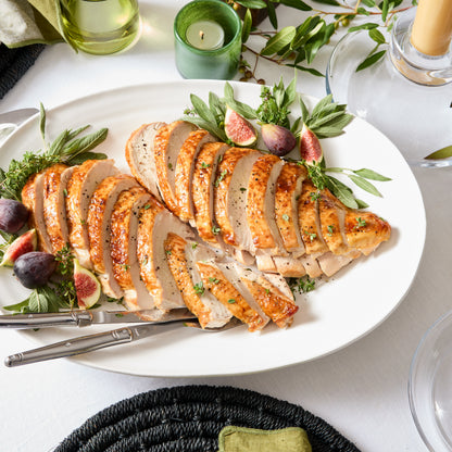 White ceramic oval platter with sliced turkey, figs, and herbs.