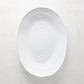 White ceramic oval serving platter with a subtle spiral design, 17"L x 12.5"W.