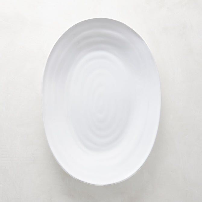 White ceramic oval serving platter with a subtle spiral design, 17"L x 12.5"W.