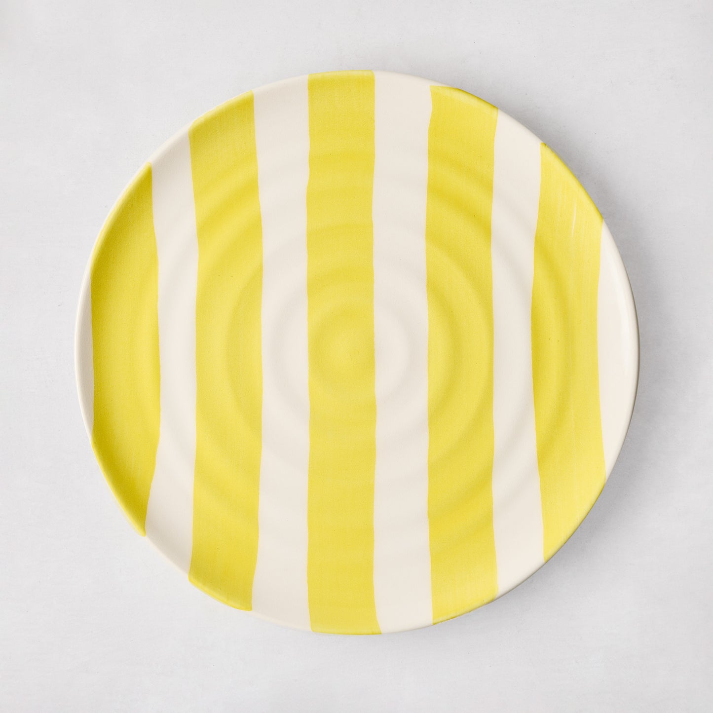 Handmade Italian ceramic salad plate with yellow vertical stripes and subtle spiral grooves.