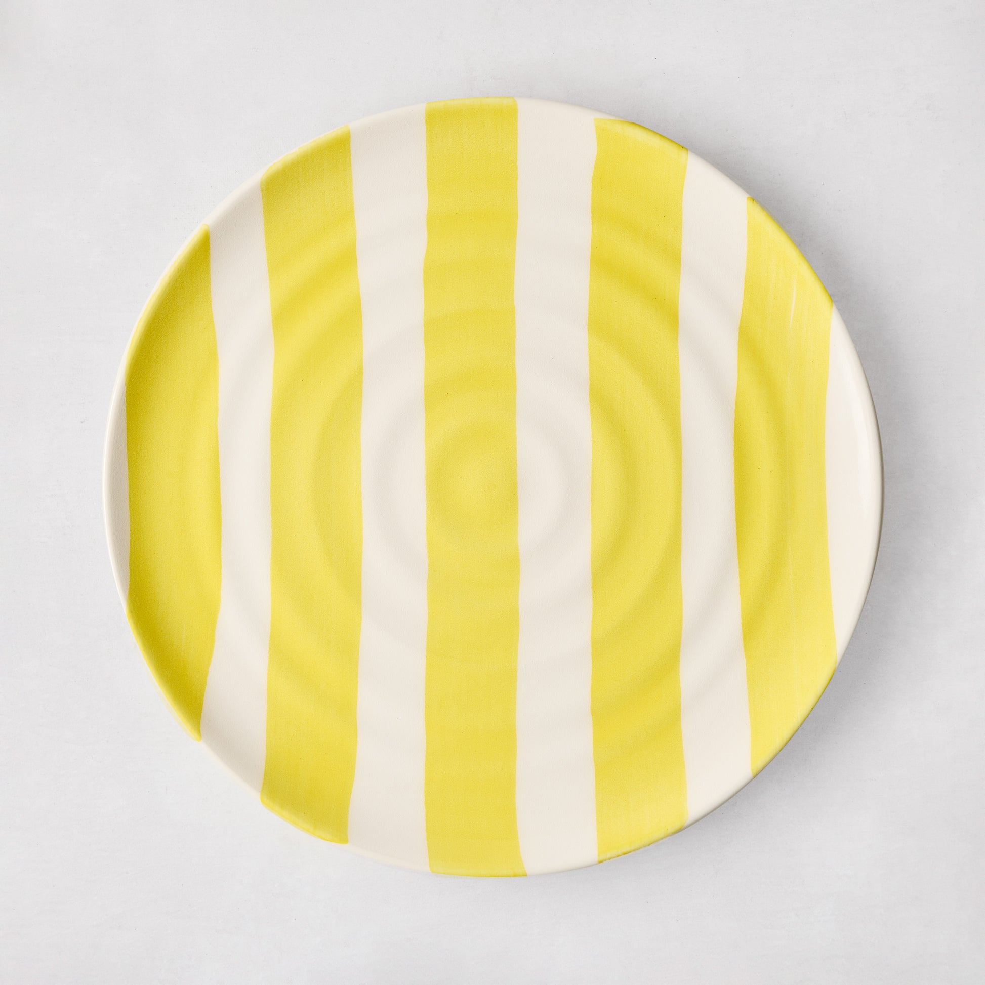 Handmade Italian ceramic salad plate with yellow vertical stripes and subtle spiral grooves.