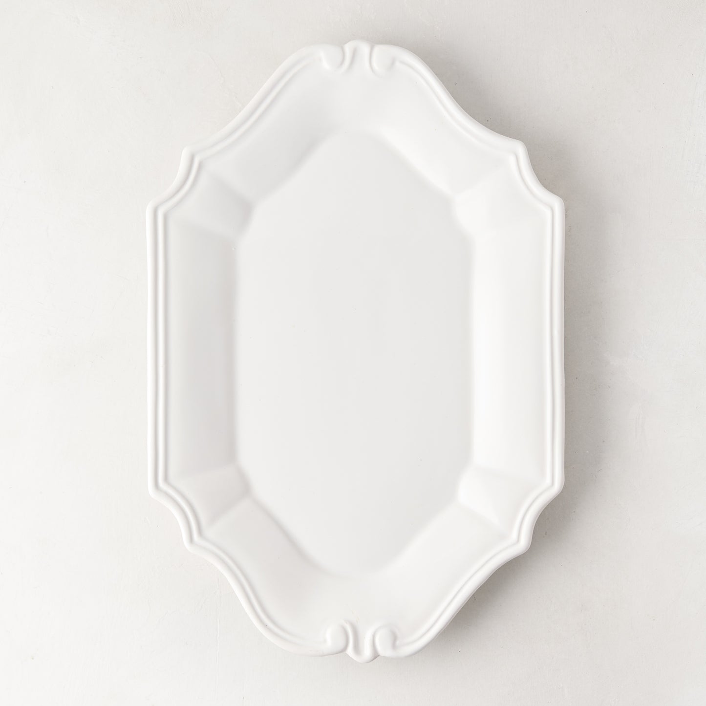 Sprezzatura white ceramic serving platter with decorative scalloped edges, 11.8"L x 8.25"W.