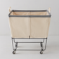 Steele 3-Bushel Canvas Elevated Rolling Laundry Hamper with cream canvas and dark trim on a black steel frame.