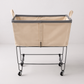 Steele 4-Bushel elevated rolling laundry hamper with natural canvas basket, gray trim, and black steel frame.