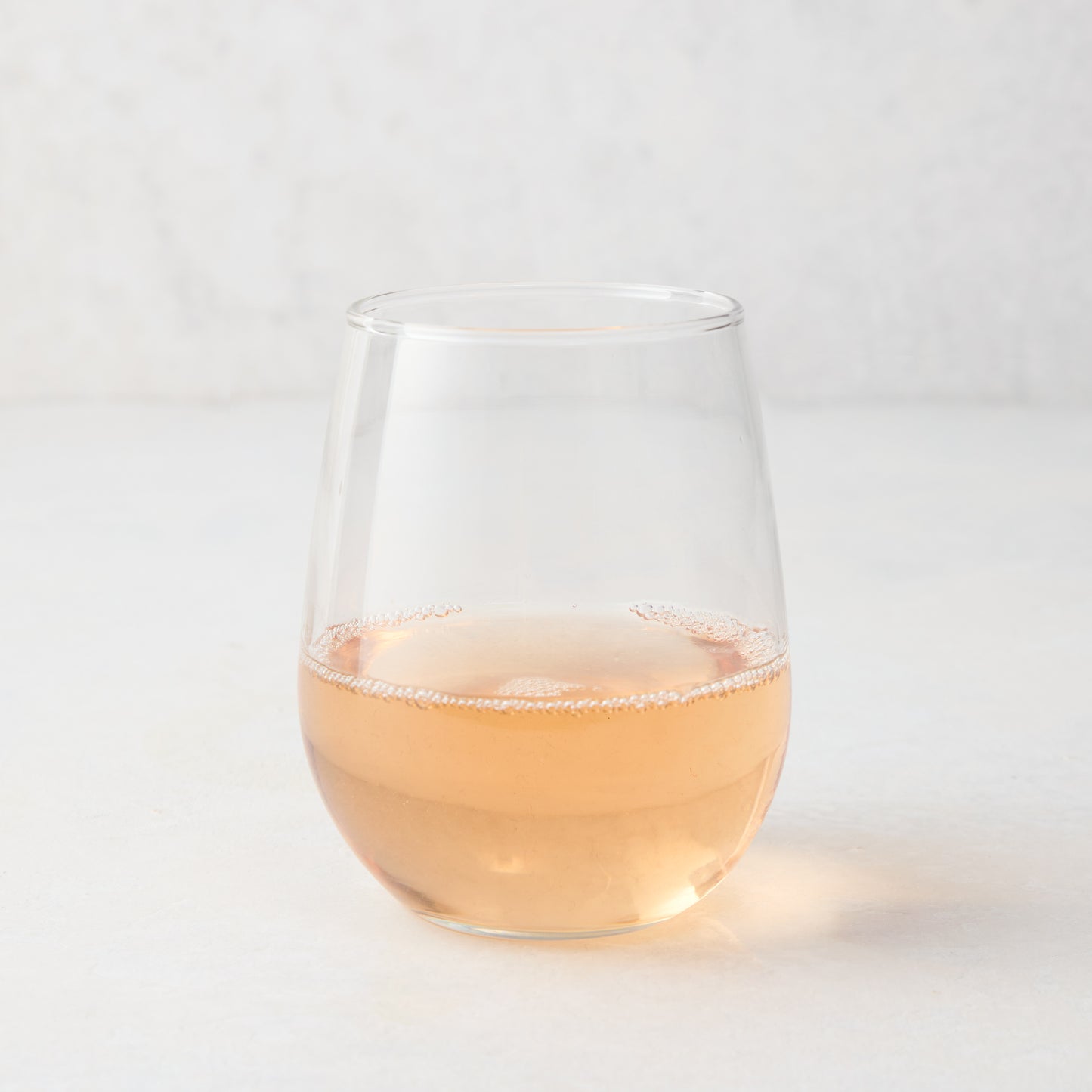 Clear stemless all-purpose glass filled with light pink rosé wine, 16.75 oz. capacity.