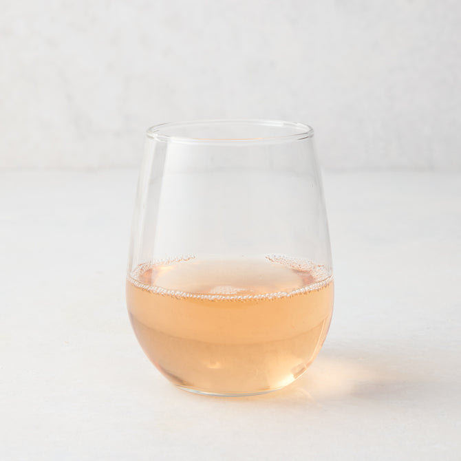 Clear stemless all-purpose glass filled with light pink rosé wine, 16.75 oz. capacity.
