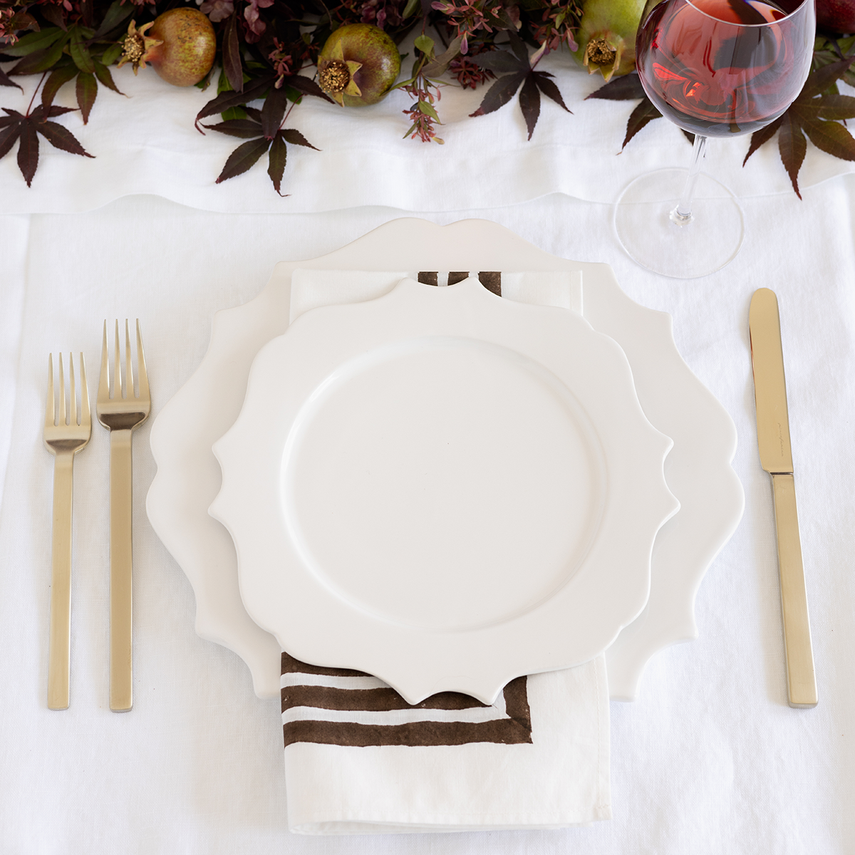 Stile Ice Champagne 5-piece flatware set: two gold forks and a gold knife on a white tablecloth.