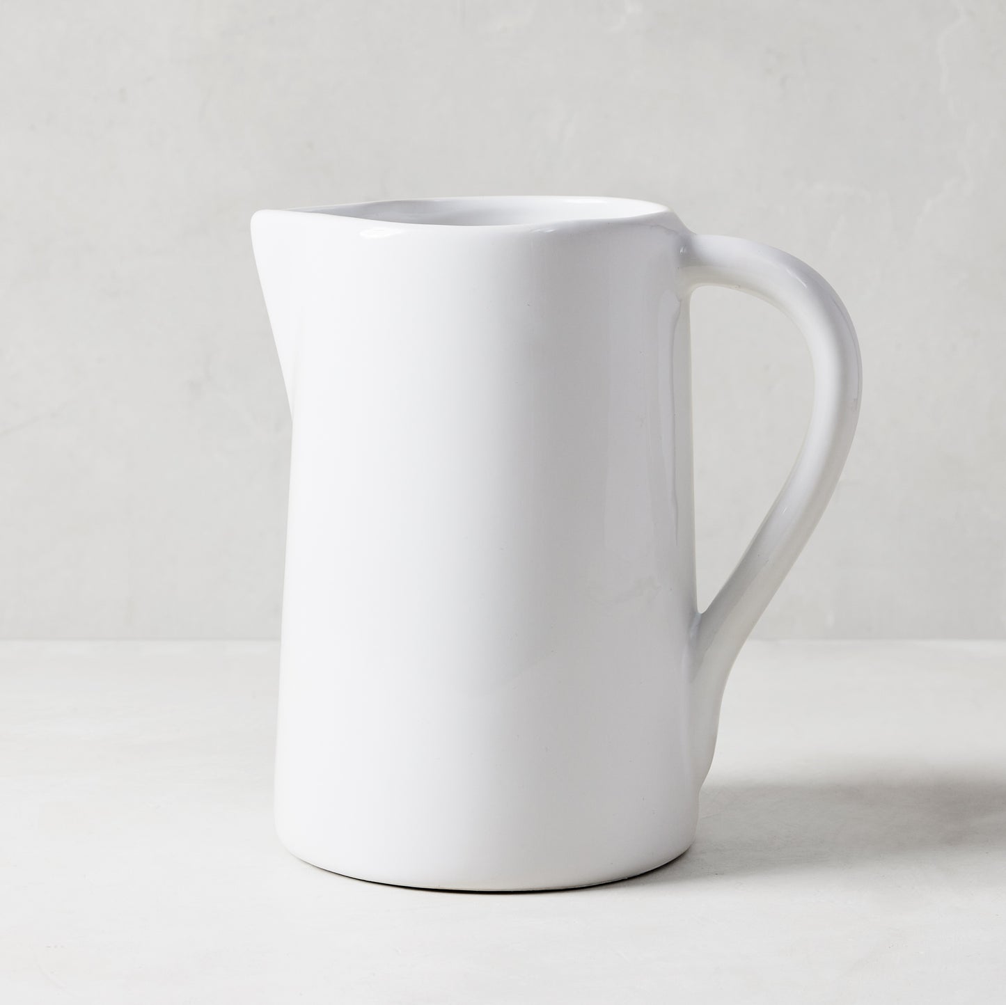 White ceramic pitcher with a large handle and spout, handmade in Italy.