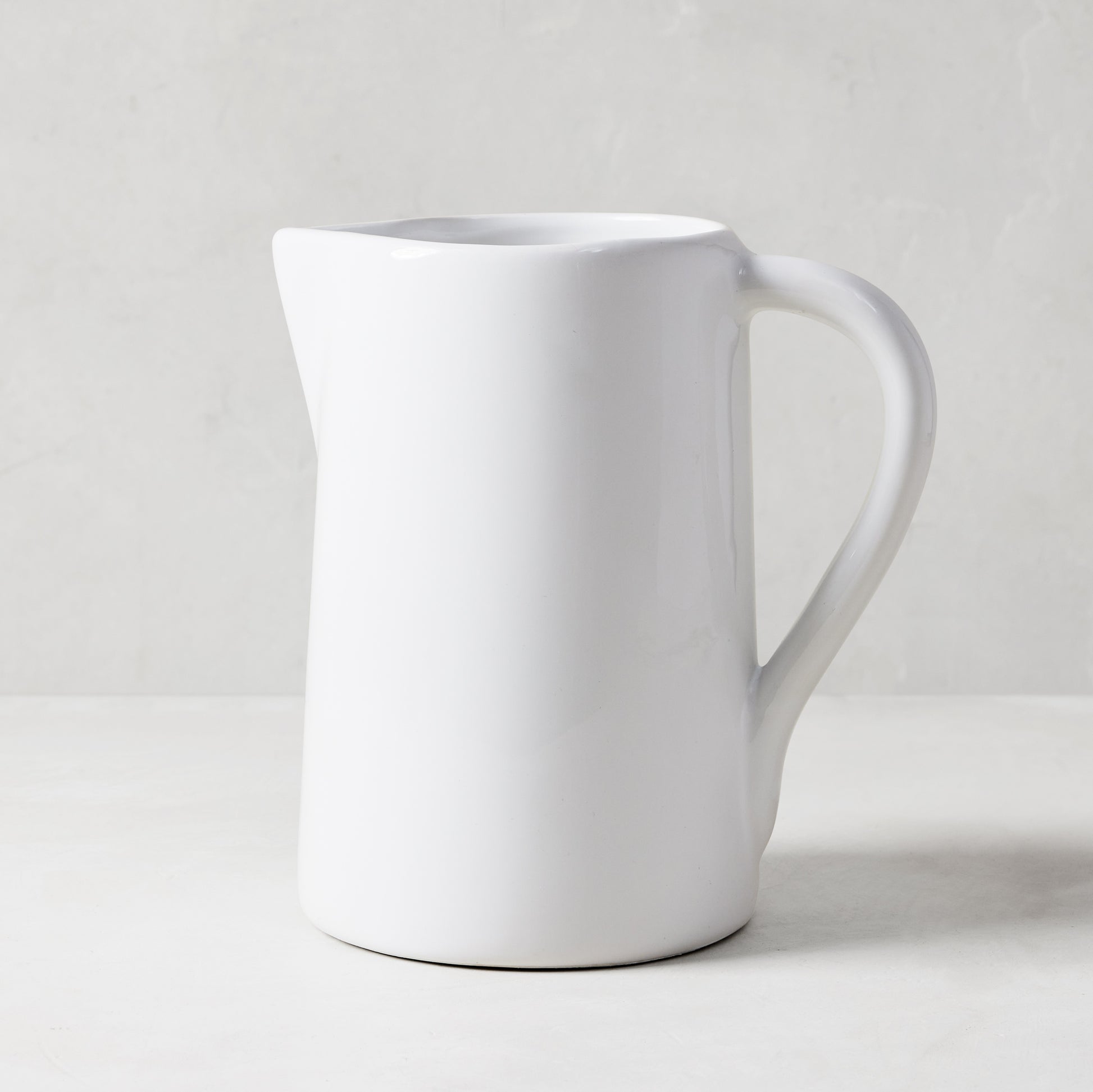 White ceramic pitcher with a large handle and spout, handmade in Italy.