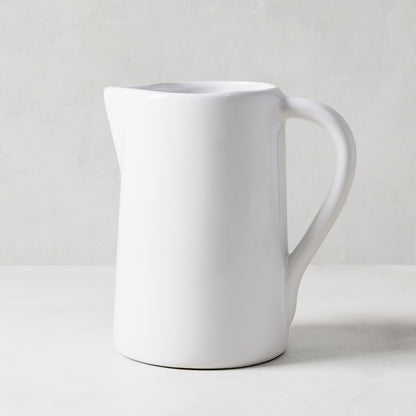 White ceramic pitcher with a large handle and spout, handmade in Italy.