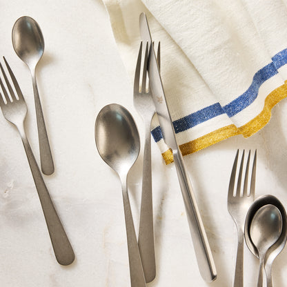 Stoccolma Pewter 5-piece flatware set, 18/10 stainless steel with a mirror finish, on marble.
