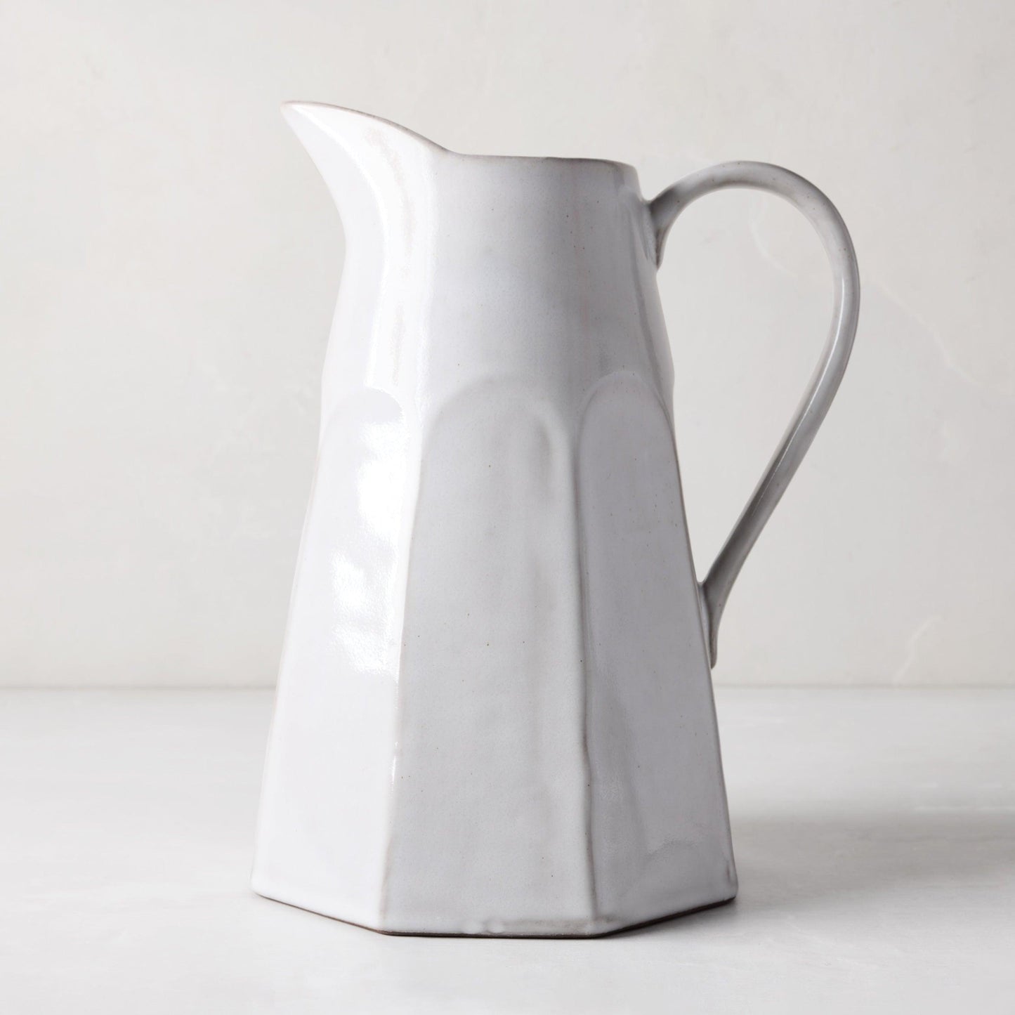 Stone grey terracotta pitcher, hand-glazed, with a faceted body and handle.