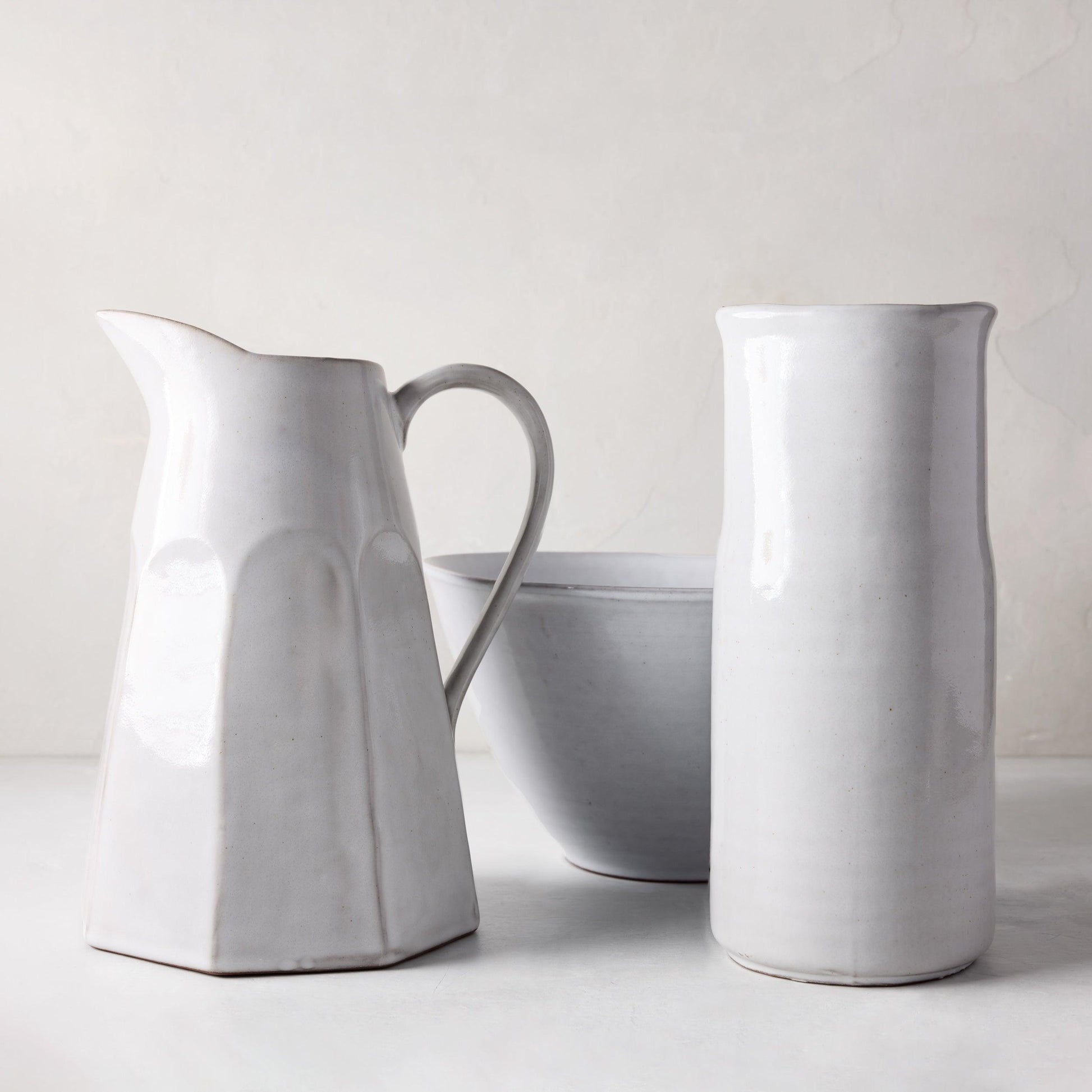 Stone grey hand-glazed terracotta water jug with handle, 10" high, next to a matching vase and bowl.