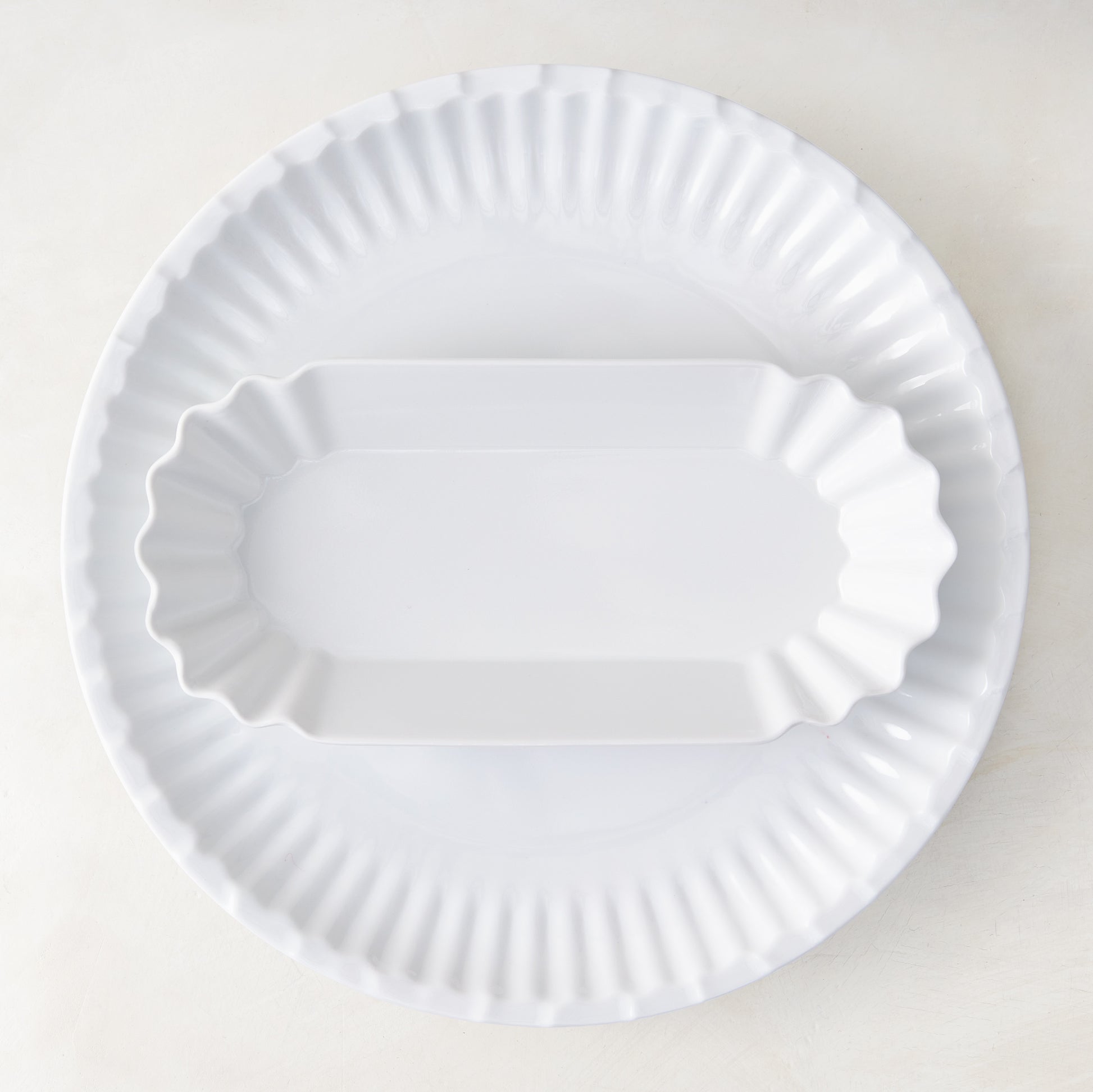 White Melamine Street Eats Hot Dog Holder, 9"L x 4"W, with scalloped edges, on a larger round plate.