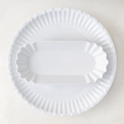White Melamine Street Eats Hot Dog Holder, 9"L x 4"W, with scalloped edges, on a larger round plate.