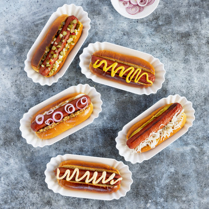 Melamine Street Eats Hot Dog Holder, white, 9"L x 4"W, with five hot dogs and toppings.