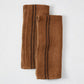 Set of 2 folded brown French linen hand towels with black stripes.